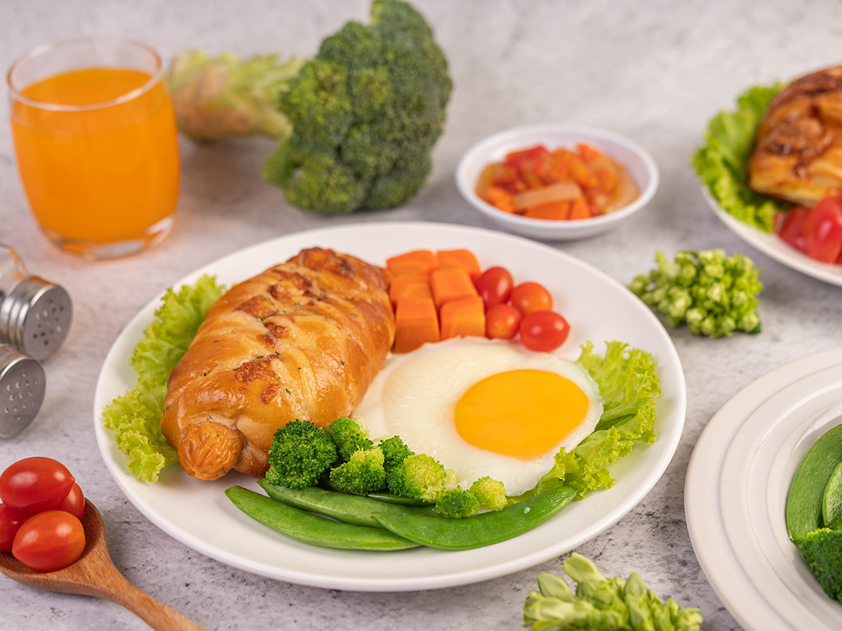 breakfast consisting bread fried eggs broccoli carrots tomatoes lettuce white plate