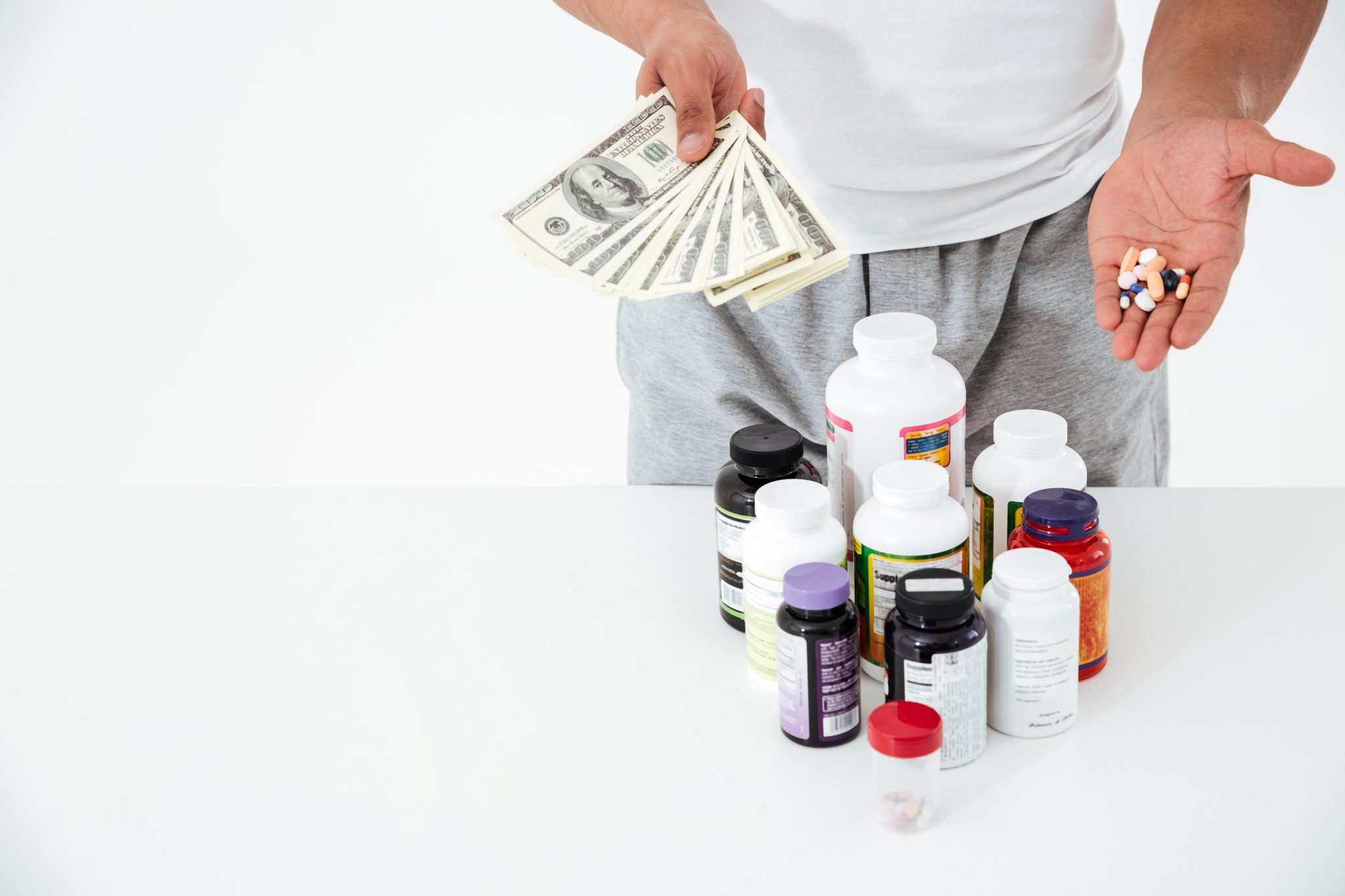 cropped image of young sportsman holding vitamins and money.